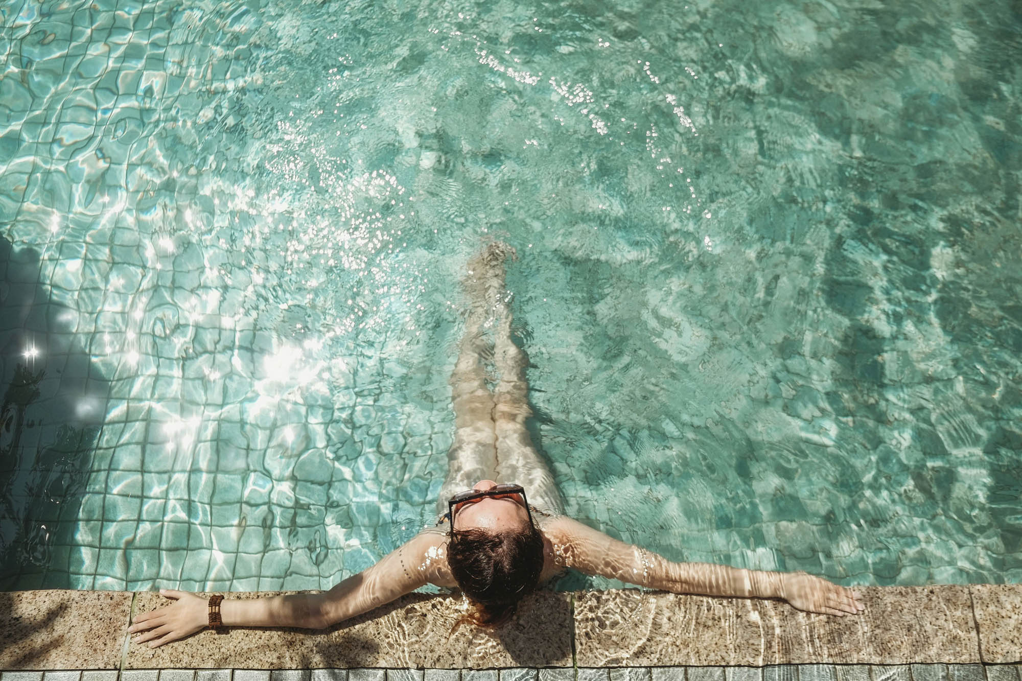 Young woman relaxing in the sunny swimming pool